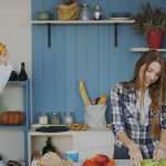 Attractive loving couple having fun in the kitchen. Handsome man juggle with fruits to impress his girlfriend at home