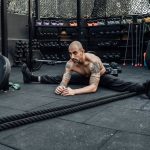 A shirtless man stretches in a modern indoor gym in Mexico City, showcasing fitness and determination.